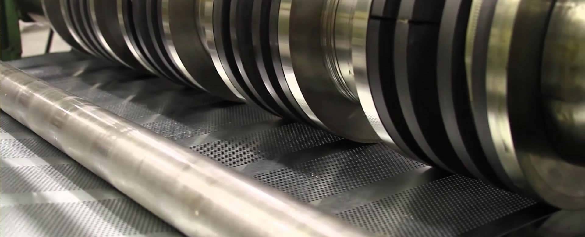 A flatten machine is planishing a piece of perforated metal sheet.