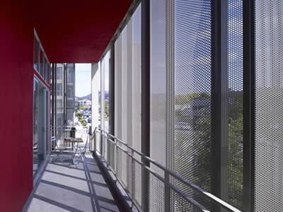 There is a desk and three chairs in the corridor and some perforated sunshade panels installed outside.