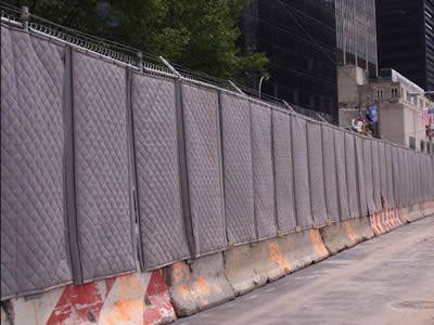 Flexible noise barrier is installed on fence with singular arm and barbed wire on its top.