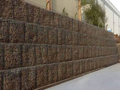 Galvanized gabion noise barrier with red stones infill is installed in the factory.