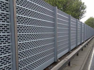 Perforated aluminum sound barrier is installed in the highway.