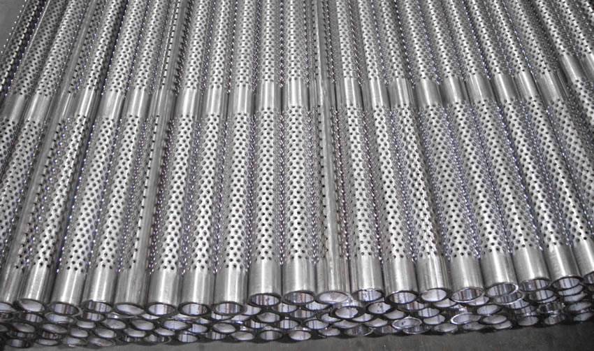Many stainless steel perforated casing pipes with round holes in warehouse.