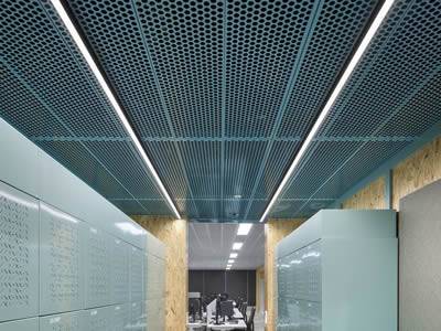 There are several closets in a locker room with a green perforated metal ceiling.
