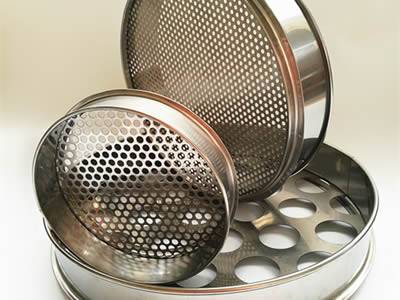 Three perforated test sieves with round holes have different sizes.