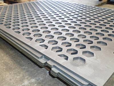 Several perforated vibrating screens with hexagonal holes stack together.