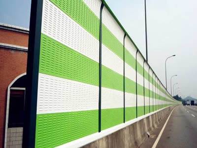 White and light green PVC sound barrier is installed between the highway and residential areas.